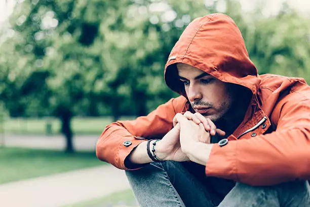 man wearing a red rain jacket contemplating in the rain