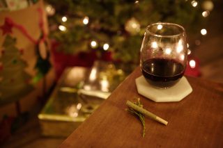 High angle closeup shot of a marijuana blunt and a glass of cognac on a table on blurred background